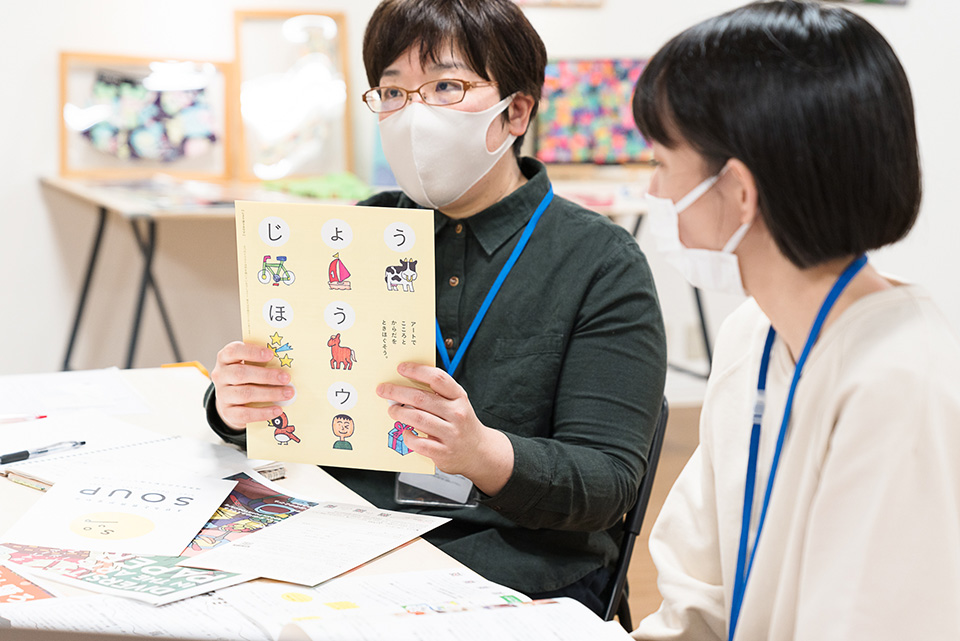 【写真】冊子「じょうほうスウプ」を手に話をする柴崎さん