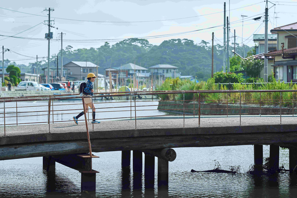 【場面写真】小学生時代の主人公が橋を渡っている